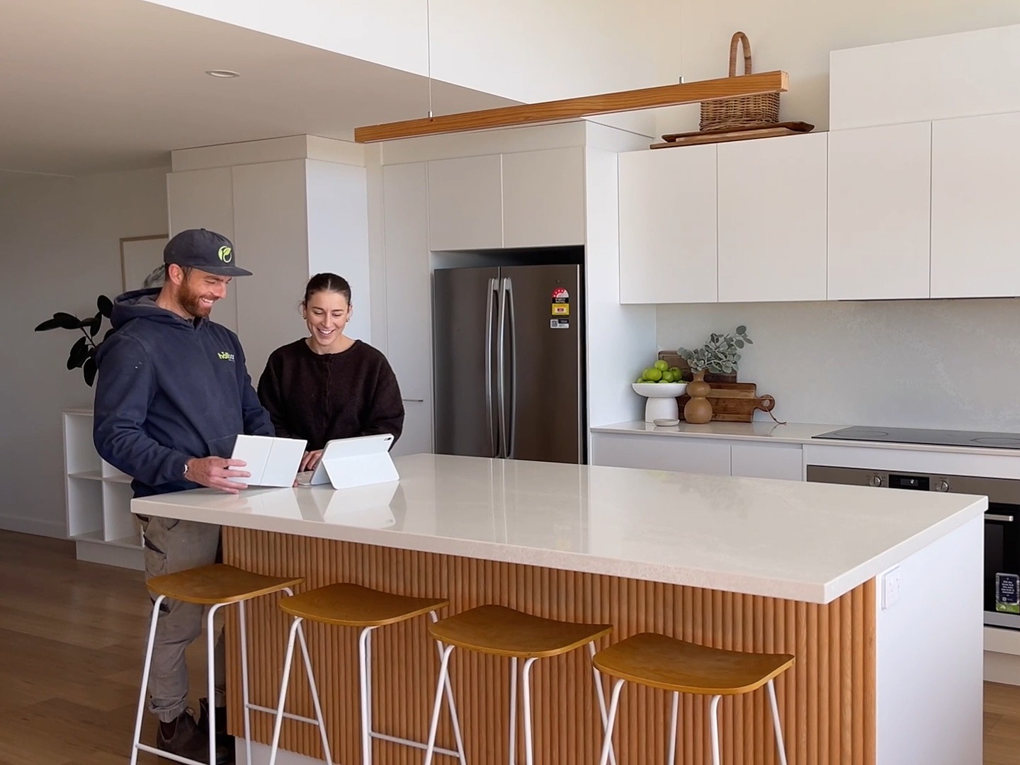 Patrik Bergman and a client going through plans on a tablet at the Calga Crescent kitchen island